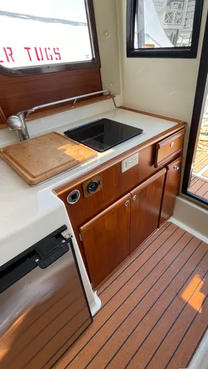  Yacht Photos Pics 2022 Ranger Tugs R-25 interior kitchen with sink, wooden cabinetry, and cutting board.