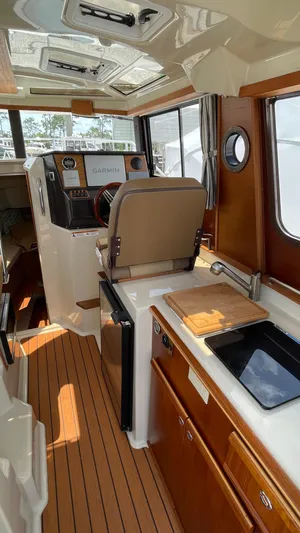  Yacht Photos Pics Interior of 2022 Ranger Tugs R-25 boat with helm, kitchenette, and wood accents.