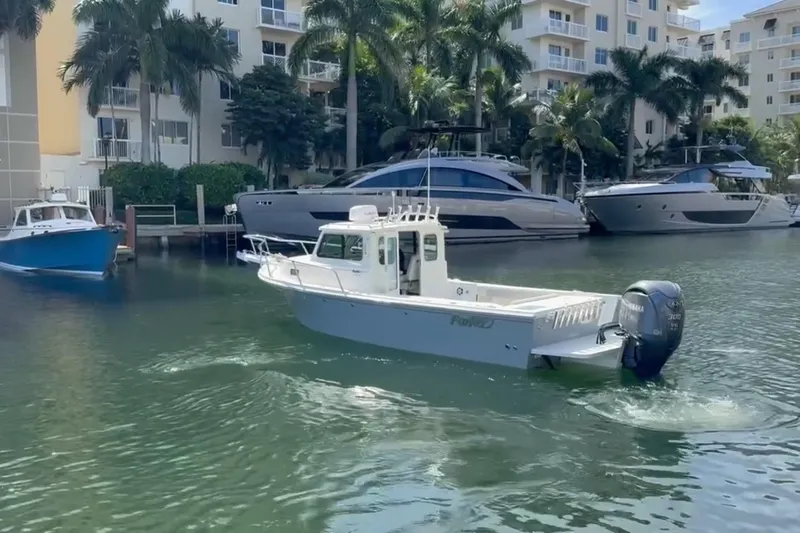  Yacht Photos Pics 2023 Parker 2320 Sport Cabin boat cruising in a marina with palm trees and yachts.