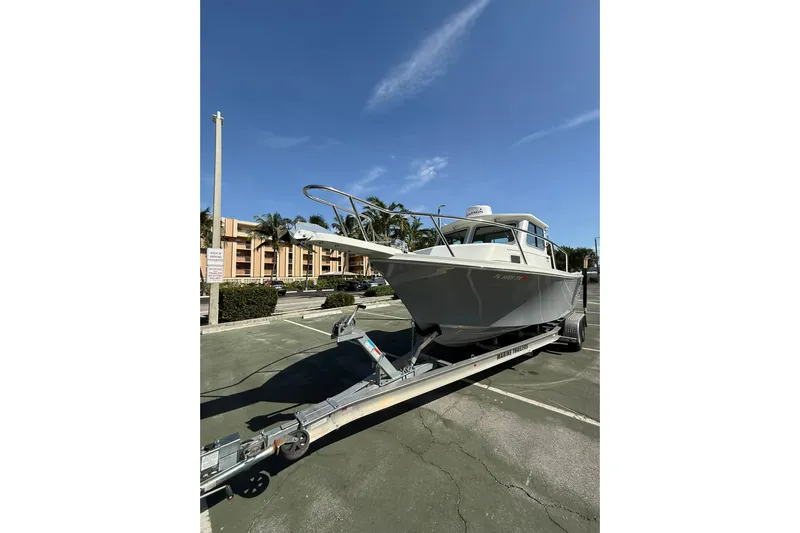  Yacht Photos Pics 2023 Parker 2320 Sport Cabin boat on trailer in parking lot under clear sky.