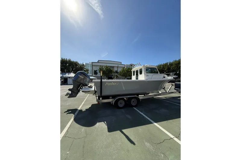  Yacht Photos Pics 2023 Parker 2320 Sport Cabin boat on trailer in parking lot under clear sky.
