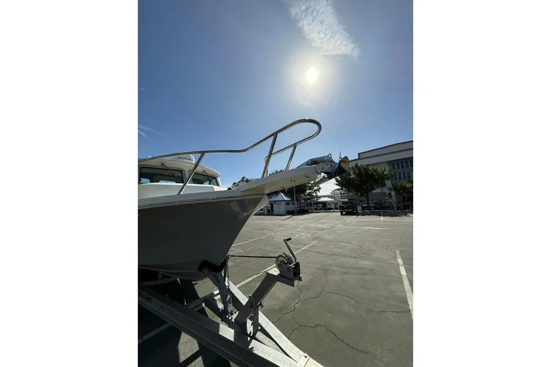  Yacht Photos Pics 2023 Parker 2320 Sport Cabin boat on trailer under bright sun in parking lot.