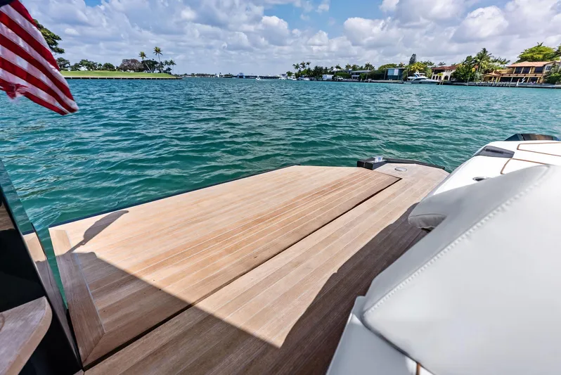 Green Eyes Yacht Photos Pics 2023 Wally Wallytender 43X yacht with wooden deck, overlooking serene waters and coastal homes.