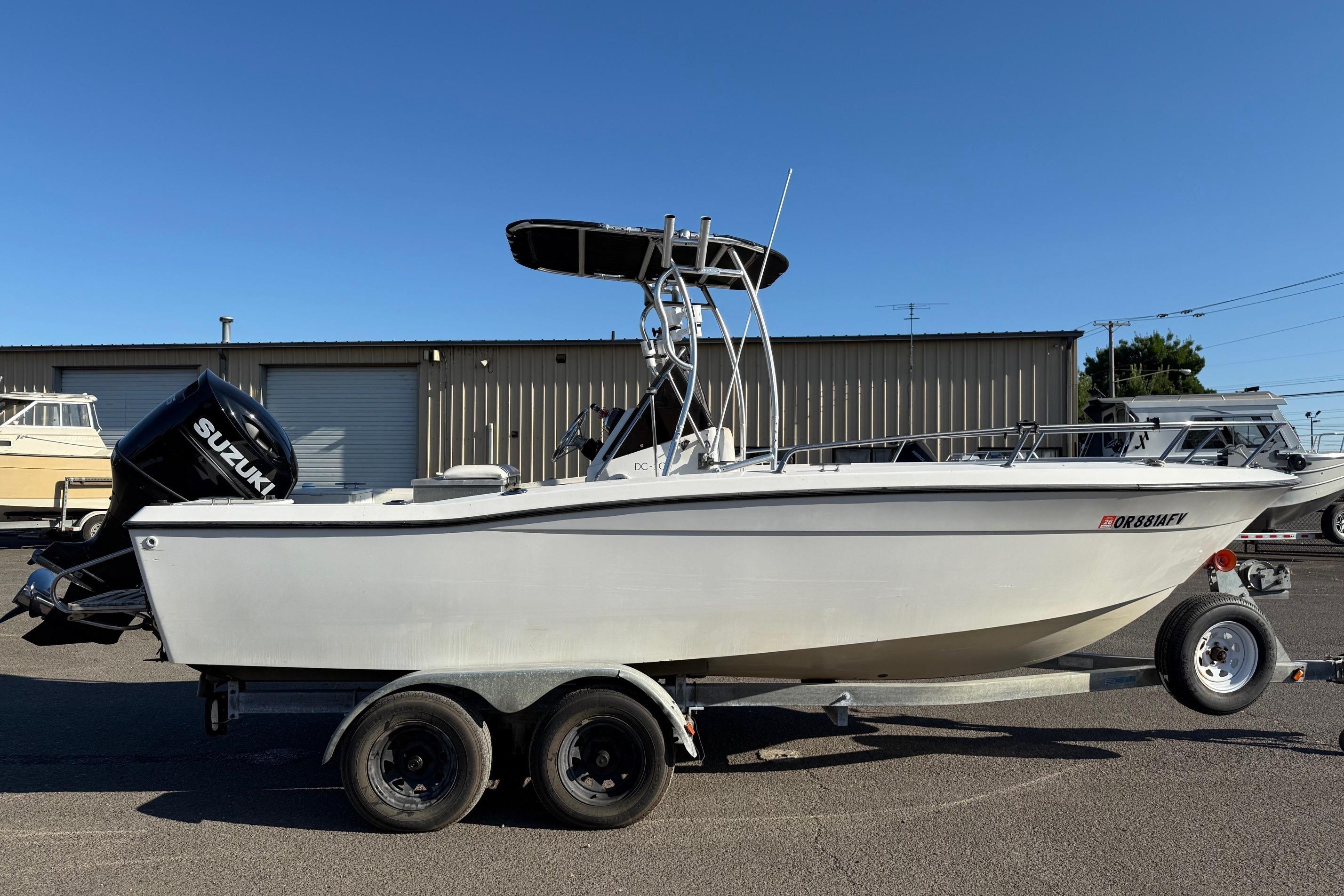1990 Larson DC-204 boat on trailer with Suzuki outboard motor, parked outdoors.