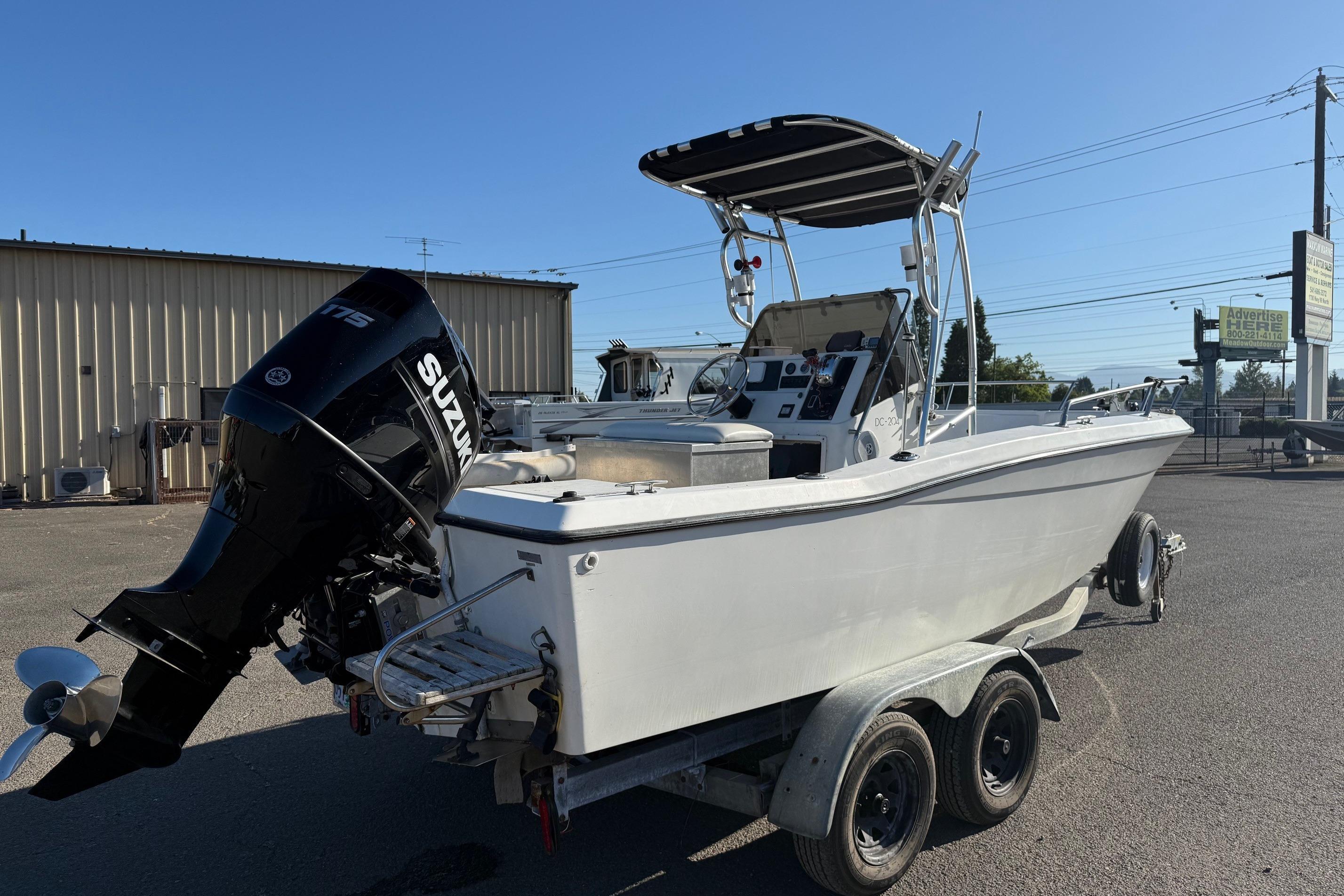1990 Larson DC-204 boat with Suzuki engine on trailer, parked outdoors.