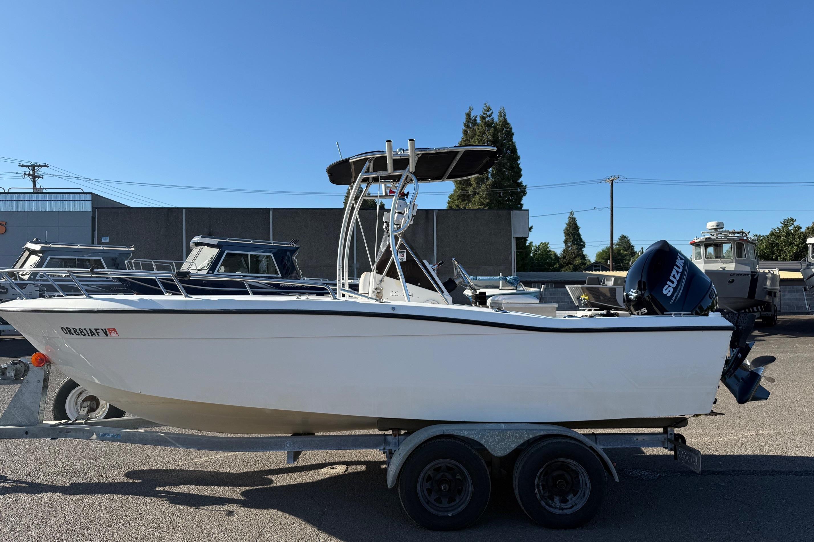 1990 Larson DC-204 boat on trailer with Suzuki outboard motor, parked outdoors.