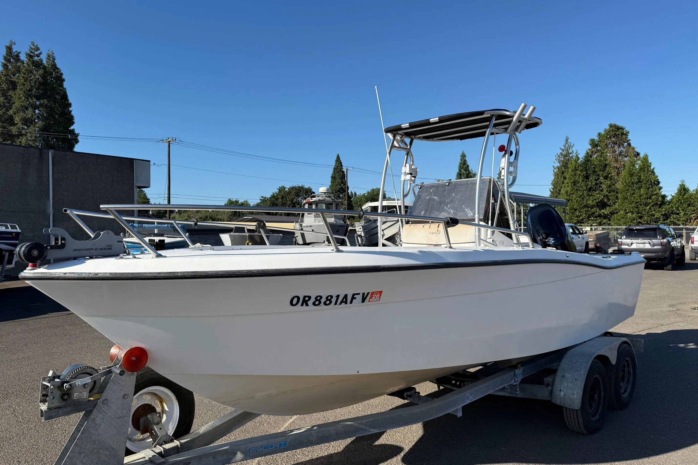 1990 Larson DC-204 boat on trailer, parked outdoors under clear blue sky.