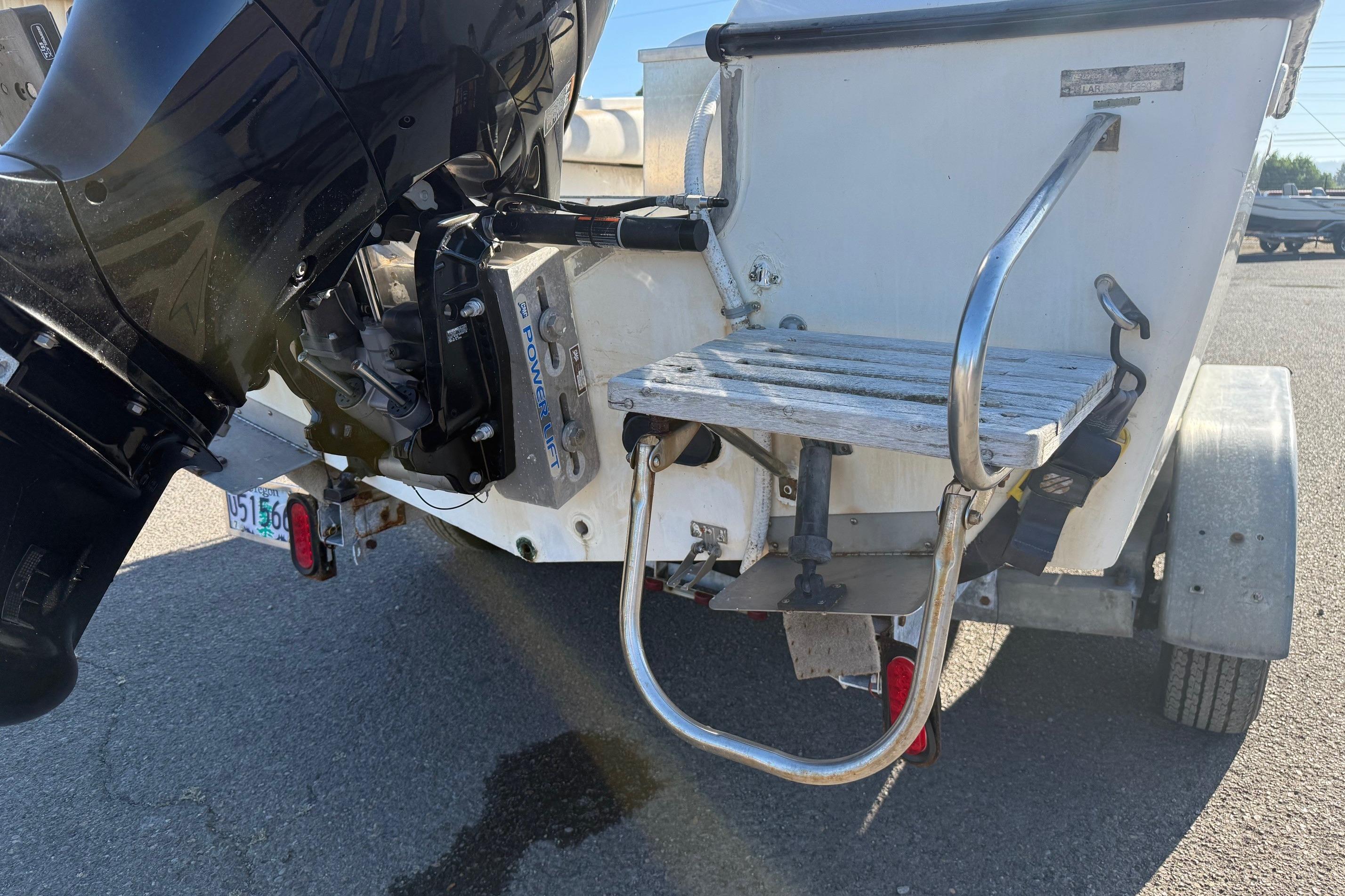 Rear view of a 1990 Larson DC-204 boat with outboard motor and swim platform.