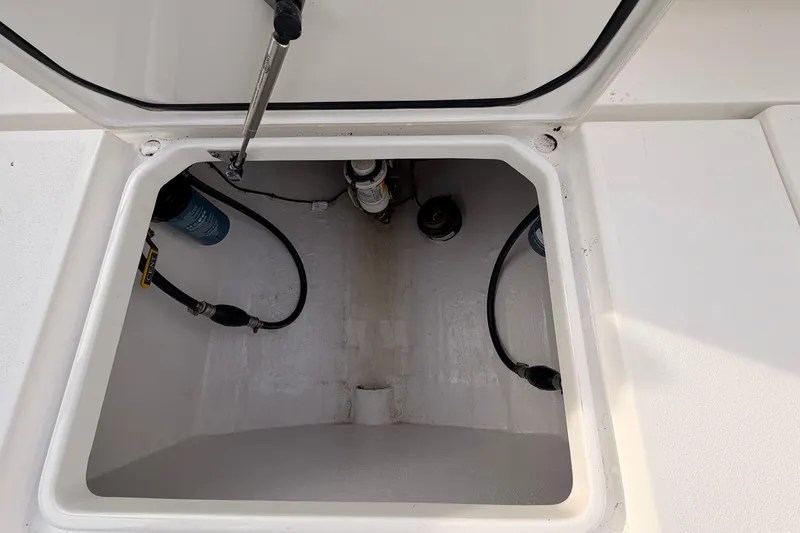  Yacht Photos Pics Open storage compartment on a Contender boat with visible hoses and fittings.