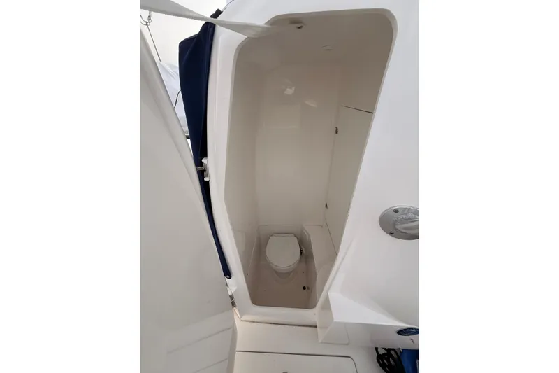  Yacht Photos Pics Compact marine toilet in a Contender boat, featuring a white interior and privacy curtain.