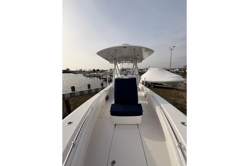  Yacht Photos Pics Contender boat with blue seating, docked near a marina under a cloudy sky.