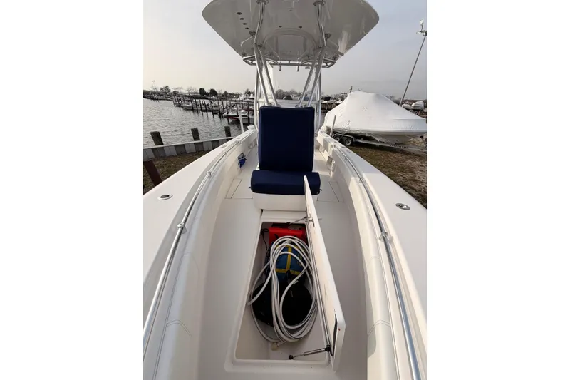  Yacht Photos Pics Contender boat interior with storage compartment, blue seating, and marina background.