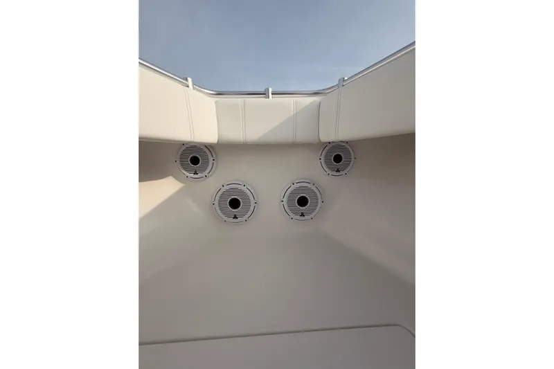  Yacht Photos Pics Contender boat interior with four circular speakers, white upholstery, and clear sky view.