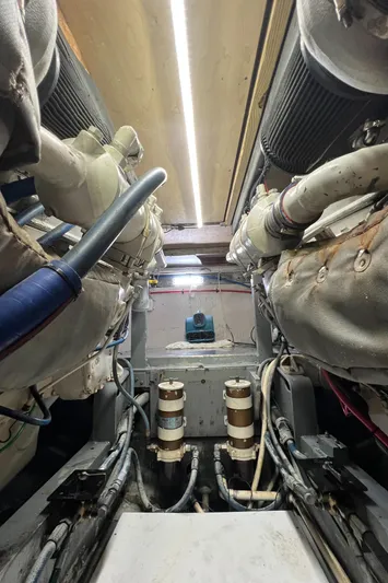  Yacht Photos Pics Engine room of a 1985 Bertram 46 Convertible boat, showcasing mechanical components and piping.