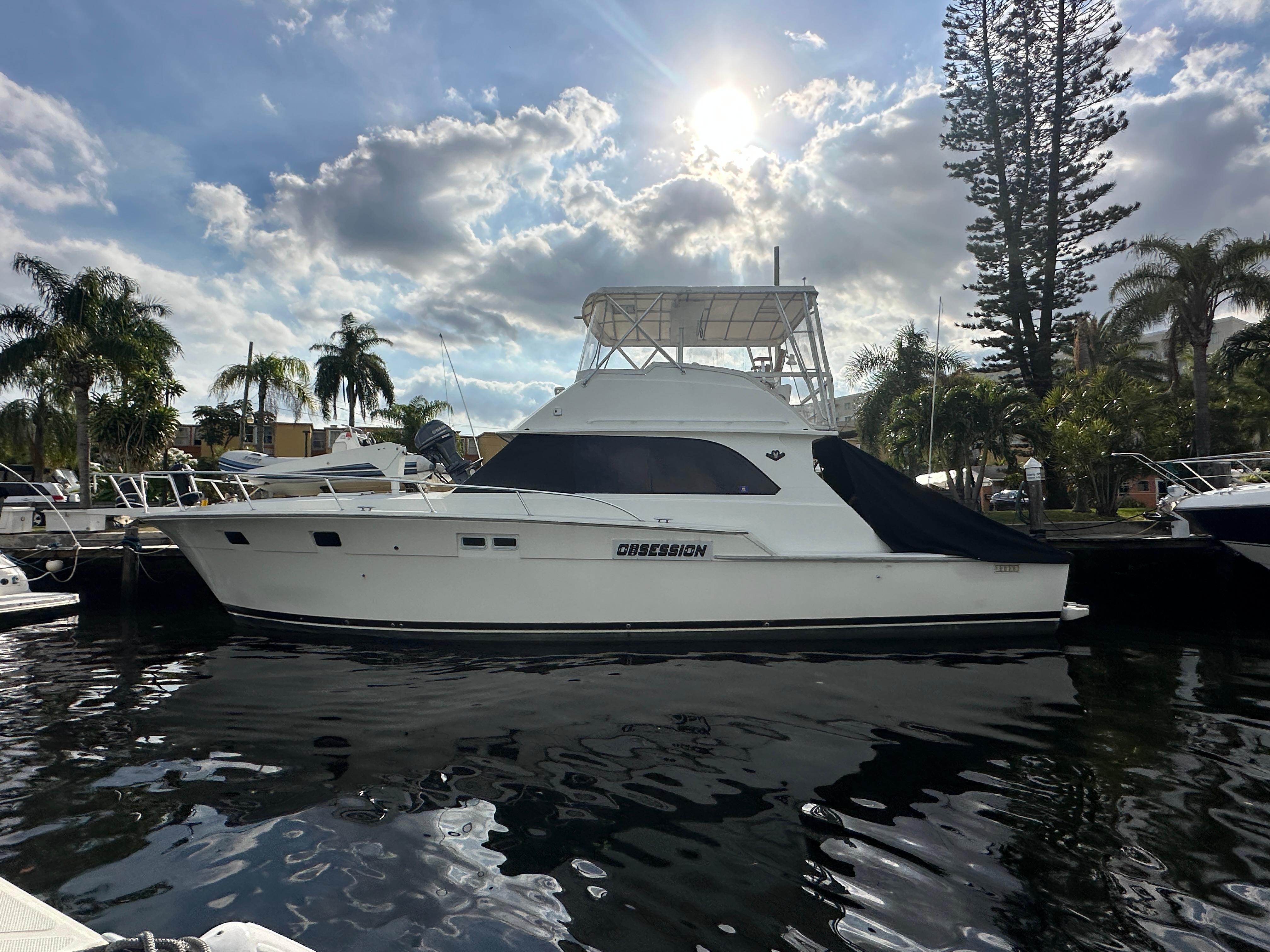 1985 Bertram 46 Convertible yacht docked under a sunny sky with palm trees.