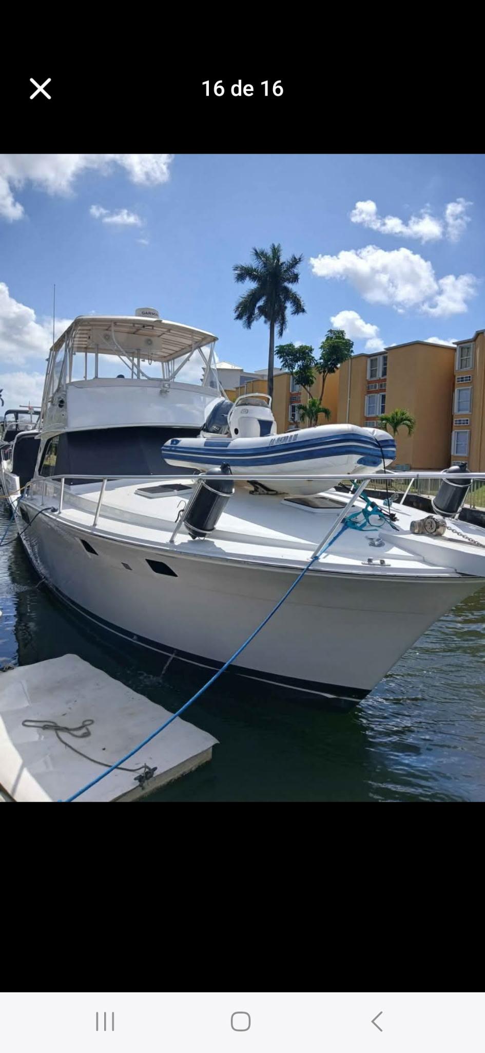 1985 Bertram 46 Convertible yacht docked under a sunny sky with palm trees.