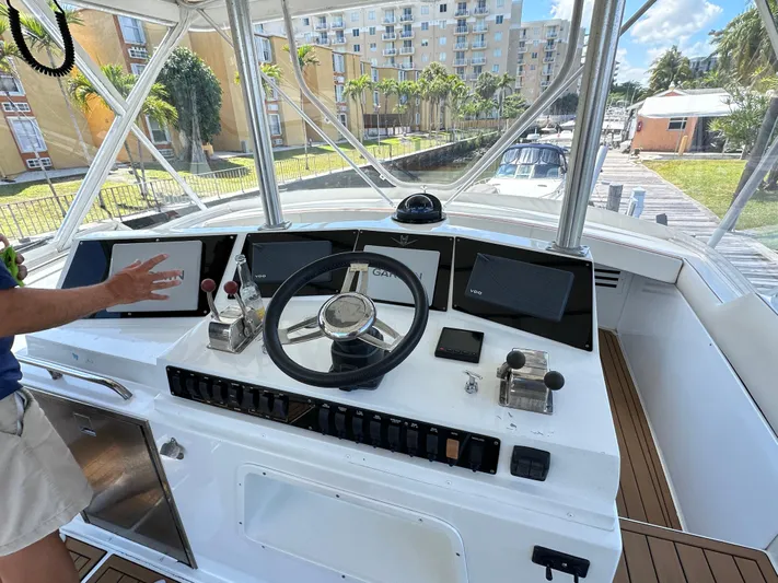  Yacht Photos Pics 1985 Bertram 46 Convertible yacht helm with modern controls and steering wheel, docked near buildings.
