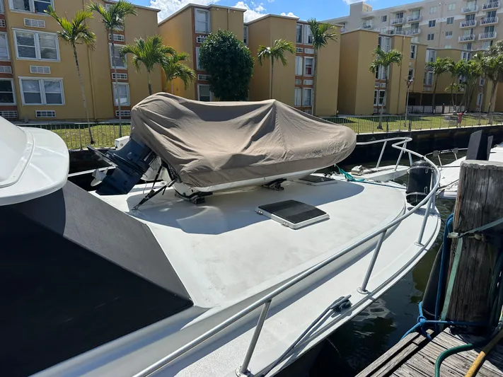  Yacht Photos Pics 1985 Bertram 46 Convertible yacht docked, covered equipment on deck, with buildings and palm trees in background.