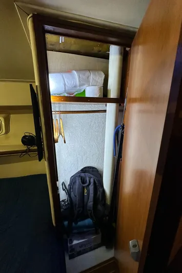 Yacht Photos Pics 1985 Bertram 46 Convertible interior closet with hangers, backpack, and bedding.