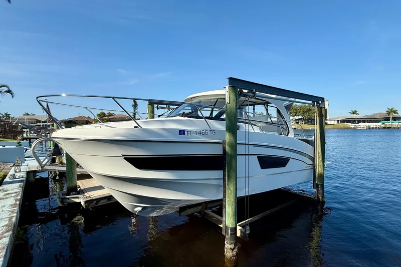  Yacht Photos Pics 2022 Beneteau Antares 9 boat docked on a lift by the water.