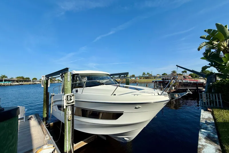  Yacht Photos Pics 2022 Beneteau Antares 9 docked by a scenic waterfront under a clear blue sky.