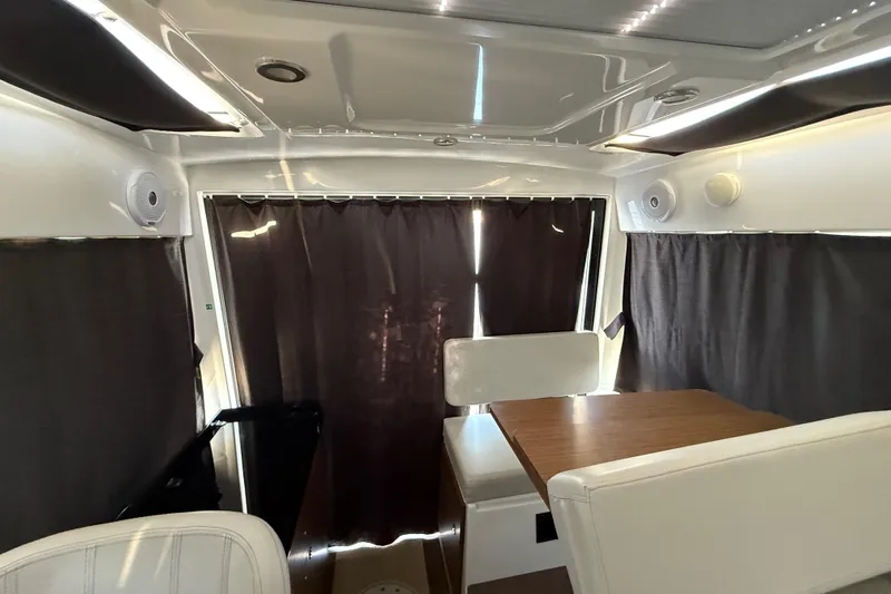  Yacht Photos Pics Interior of 2022 Beneteau Antares 9 with seating and table, curtains drawn.