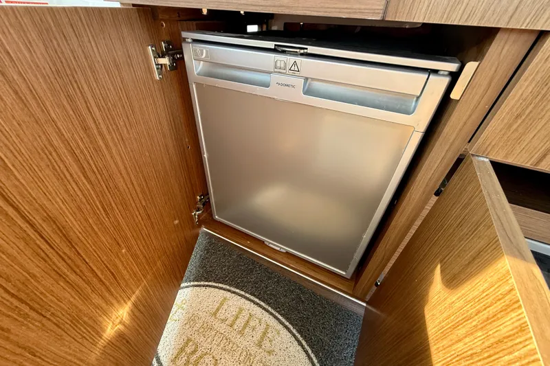  Yacht Photos Pics Compact fridge in 2022 Beneteau Antares 9 boat interior, wooden cabinetry.