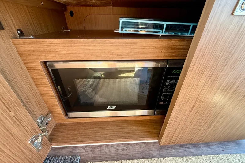  Yacht Photos Pics Microwave in 2022 Beneteau Antares 9 boat's wooden cabinet interior.