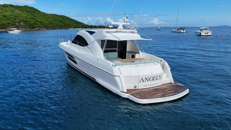  Yacht Photos Pics 2016 Riviera 5000 Sport Yacht on calm blue waters near lush green island.