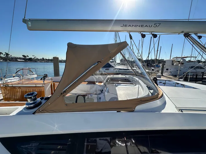 Dharma Yacht Photos Pics 2013 Jeanneau 57 sailboat with tan canopy, docked in a marina under clear skies.