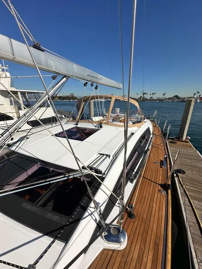 Dharma Yacht Photos Pics 2013 Jeanneau 57 yacht docked, showcasing sleek design and wooden deck.