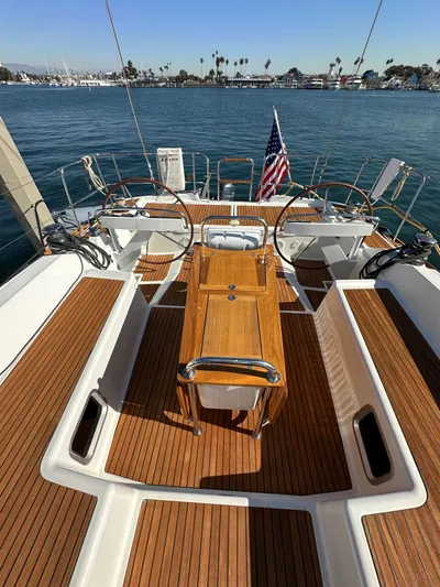 Dharma Yacht Photos Pics 2013 Jeanneau 57 sailboat deck with wooden finish, dual steering wheels, and ocean view.