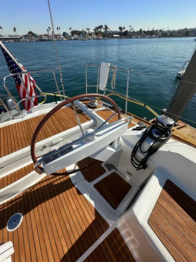 Dharma Yacht Photos Pics 2013 Jeanneau 57 sailboat deck with steering wheel, docked by calm waters.