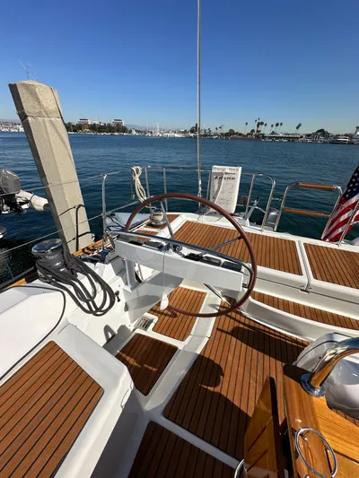Dharma Yacht Photos Pics 2013 Jeanneau 57 yacht with wooden deck, docked in a sunny marina.