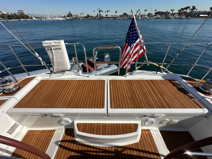 Dharma Yacht Photos Pics Jeanneau 57 sailboat deck, 2013 model, with American flag, docked in a marina.