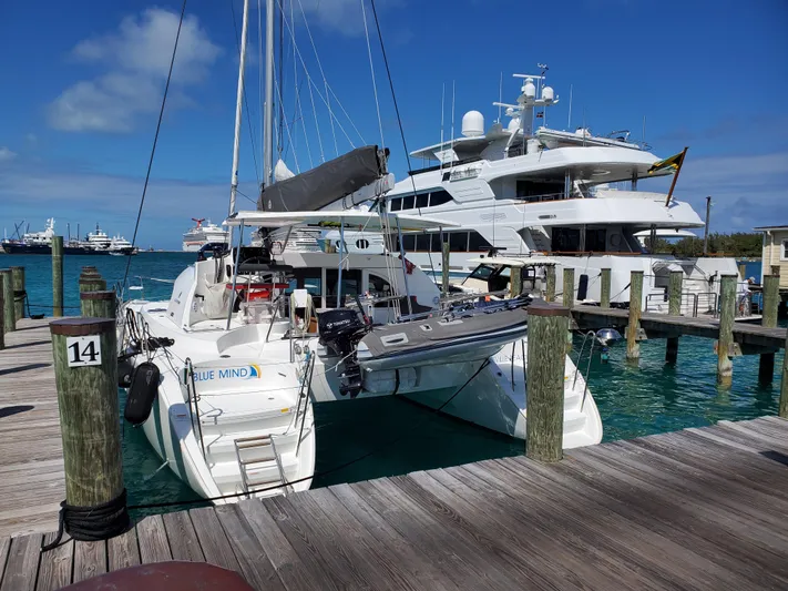 Blue Mind Yacht Photos Pics 2018 Lagoon 380 S2 catamaran docked at marina, clear blue sky, and ocean.