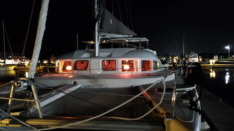 Blue Mind Yacht Photos Pics 2018 Lagoon 380 S2 catamaran docked at night with illuminated cabin windows.