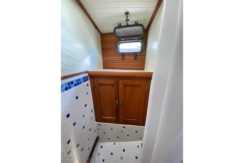 Ganache II Yacht Photos Pics Vintage 1985 Liberty 458 yacht bathroom with wooden cabinets and nautical window.