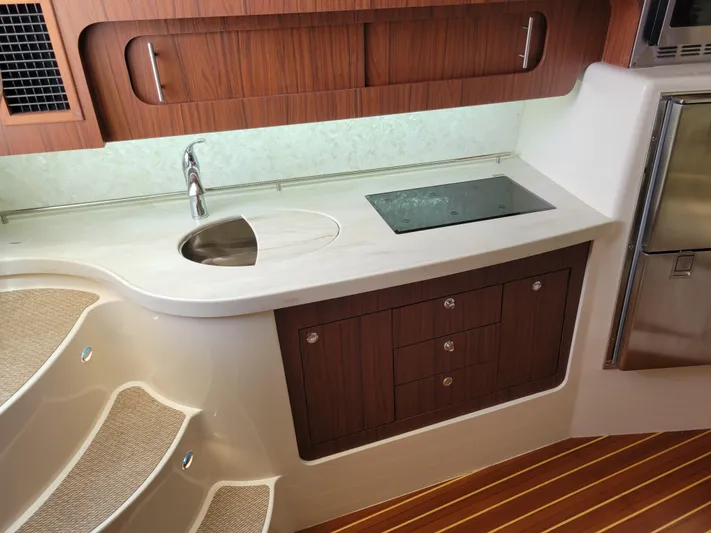  Yacht Photos Pics Luxurious 2022 Grady-White Express 370 yacht interior with modern kitchenette and wooden cabinetry.