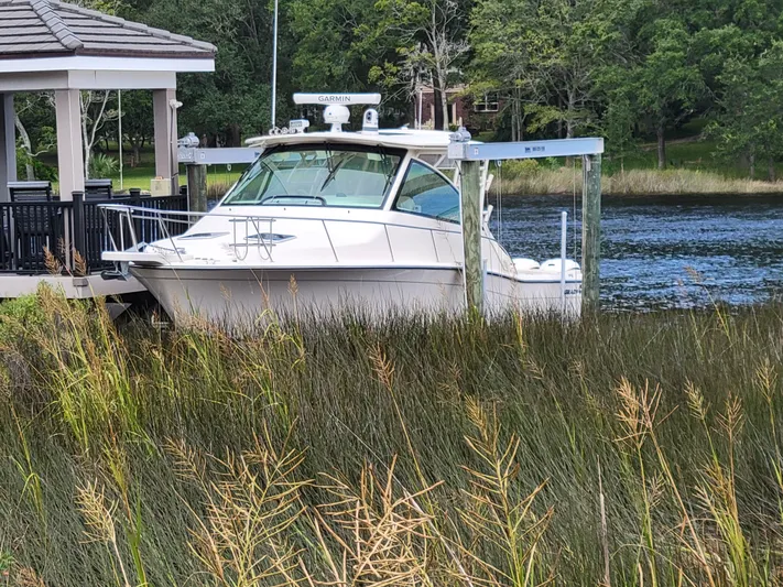  Yacht Photos Pics 2022 Grady-White Express 370 boat docked by a lakeside gazebo, surrounded by lush greenery.
