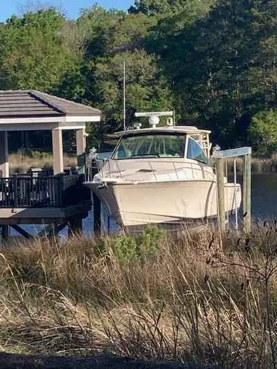  Yacht Photos Pics 2022 Grady-White Express 370 docked near a lakeside cabin, surrounded by lush greenery.