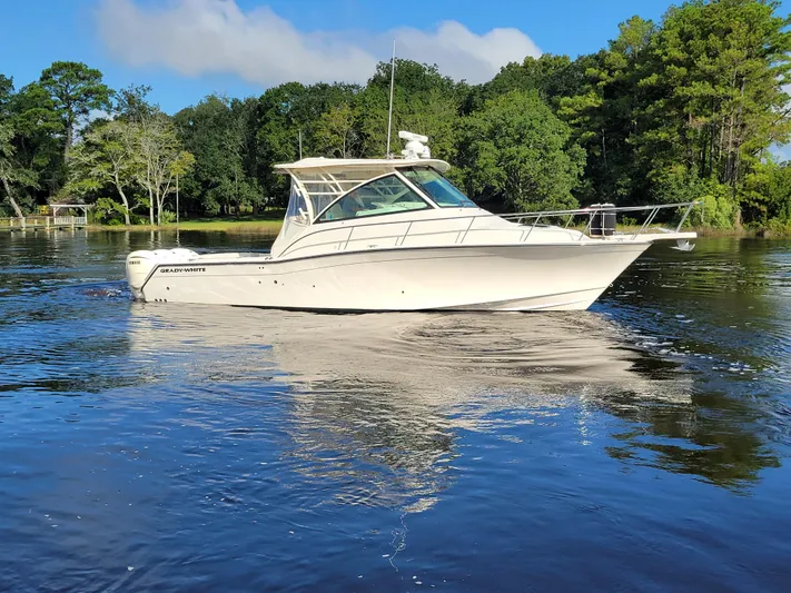  Yacht Photos Pics 2022 Grady-White Express 370 boat on calm water with lush green trees.