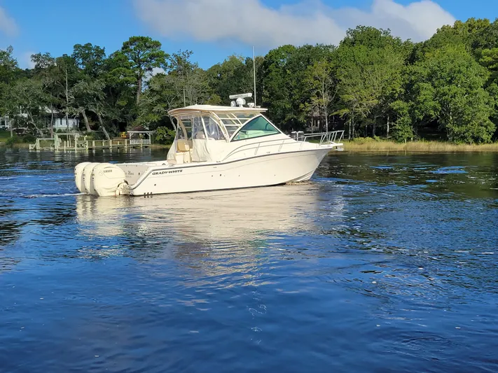  Yacht Photos Pics 2022 Grady-White Express 370 boat on calm water, surrounded by lush greenery.