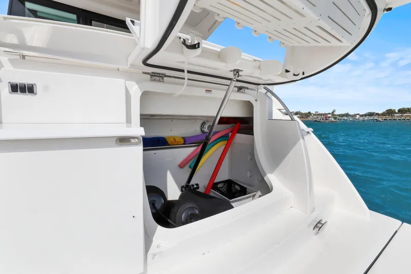 Seeker Yacht Photos Pics 2023 Tiara Yachts C49 Coupe storage compartment with pool noodles, docked by blue water.