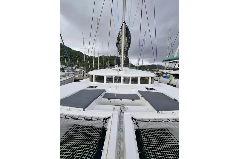  Yacht Photos Pics 2010 Lagoon 500 catamaran docked, featuring spacious deck and netting under cloudy skies.