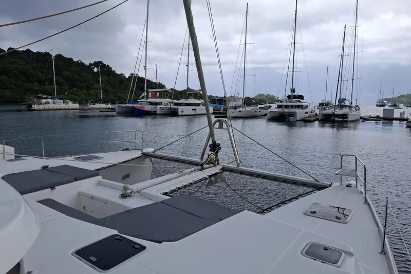  Yacht Photos Pics Lagoon 500 catamaran docked in a marina, surrounded by other sailboats, under cloudy skies.