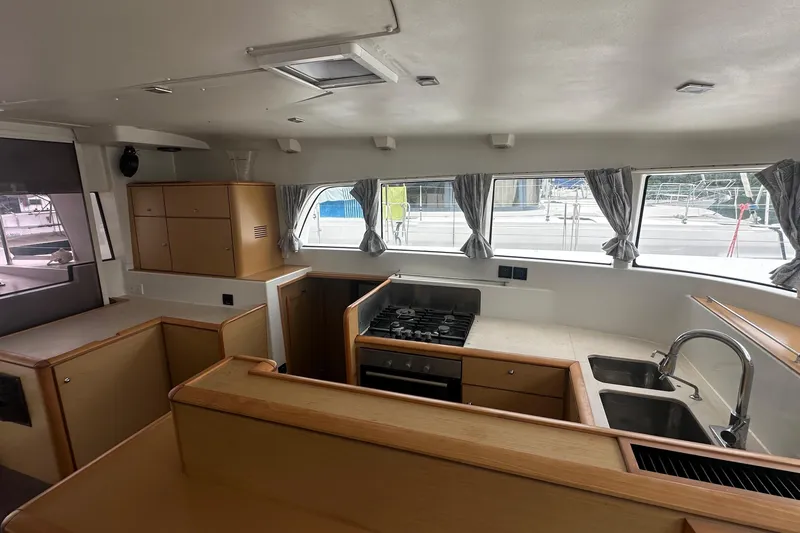 Yacht Photos Pics Interior of 2010 Lagoon 500 yacht kitchen with stove, sink, and wooden cabinetry.