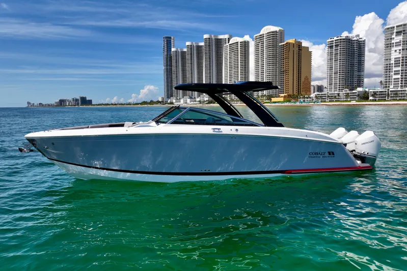  Yacht Photos Pics 2025 Cobalt R33 Outboard boat on turquoise water with city skyline background.
