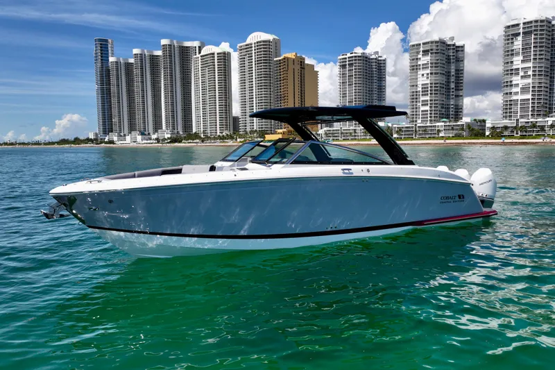  Yacht Photos Pics 2025 Cobalt R33 Outboard boat on turquoise water with city skyline background.