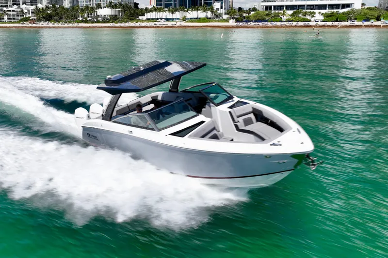  Yacht Photos Pics 2025 Cobalt R33 Outboard speeding on turquoise water near a city shoreline.